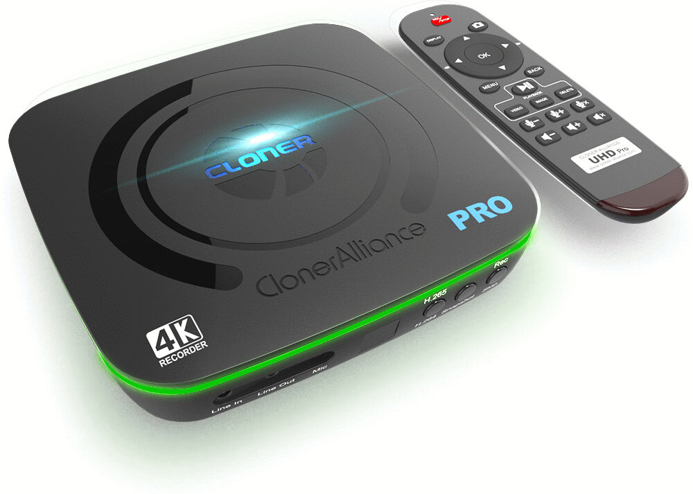 The image shows a black, rectangular device with a green border and the inscription "ClonerAlliance PRO". Next to it lies a remote control with numerous buttons.