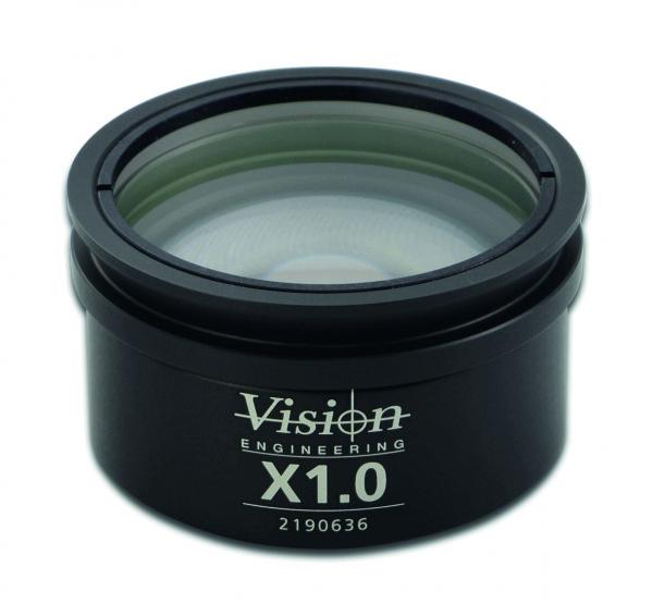 The image shows a magnifying lens in a black casing. On the front, the words "Vision Engineering" and "X1.0" are printed. The lens has a clear surface and a slightly curved edge.