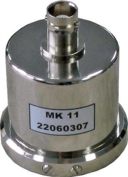 The image shows a metallic, cylindrical component with a round base and a connection on top. It has a smooth surface and bears a label with the inscription "MK 11" and a number.