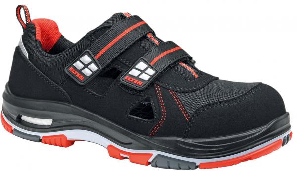 The shoe is black with red accents. It has two Velcro straps, a sporty shape, and a padded sole. The material appears sturdy and is suitable for work use.