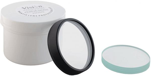 The image shows a round, clear lens with a black rim, standing on a white container. Next to the container is another round lid in light blue.