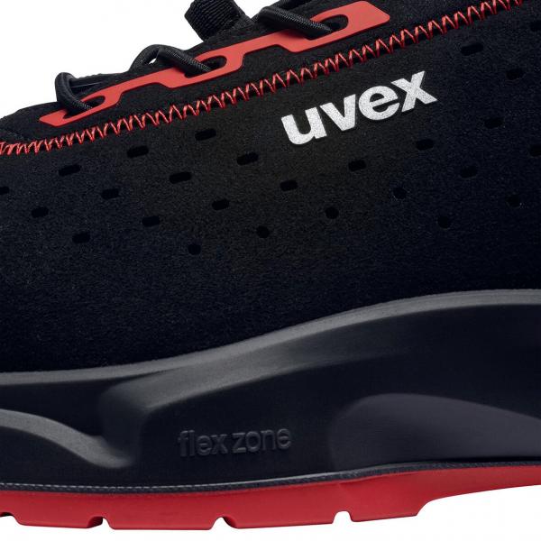 The image shows a modern, black shoe with red details. It has a textured surface with small holes for better breathability and a flexible sole.