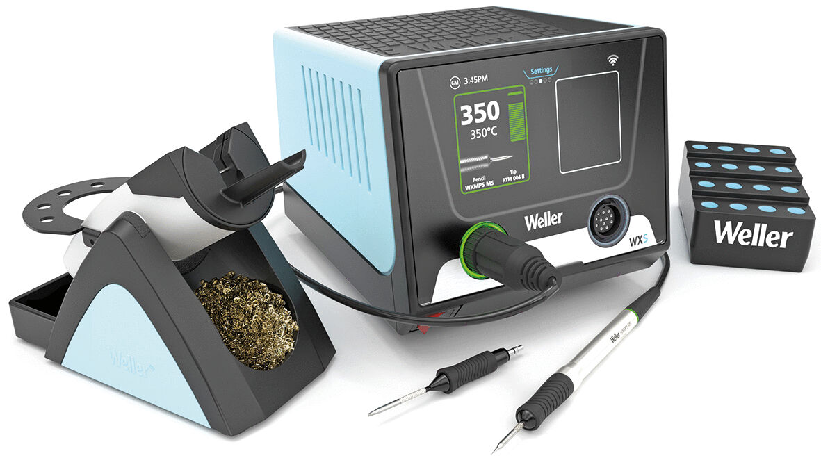 The image shows a soldering station with a digital display, equipped with a soldering tip. Next to it, there is a holder with metal shavings and a box with soldering accessories.