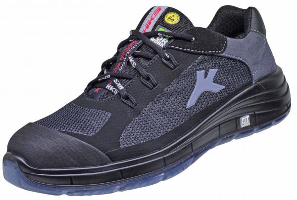 The shoe is a black, sporty work shoe with a flexible sole. It has a padded collar, laces, and a sturdy, protective toe cap.