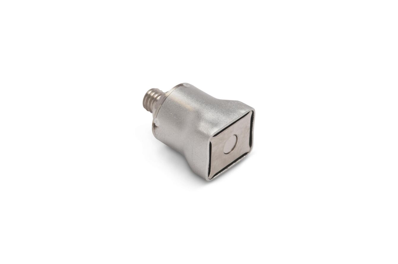 The image shows a metallic component with a square shape. It has a smooth, shiny surface and a threaded connection on one side. The other side is flat and features a small, round indentation.