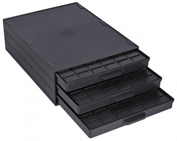 The image shows a black, flat box with three pull-out drawers. Each drawer has compartments to organize small objects. The surface is smooth and inconspicuous.