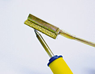 The image displays two specialized tools: a dustpan with a wide, flat edge and a brush with a yellow handle. Both are arranged on a light surface.