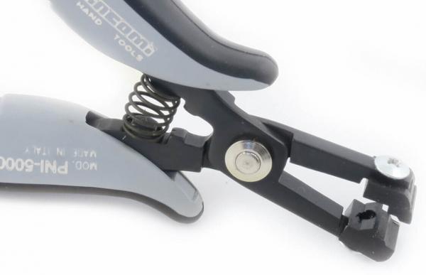 The image shows a tool with two ergonomic handles and a spring-loaded mechanism. At one end, there are two blades that close together. It has a black and gray color scheme.