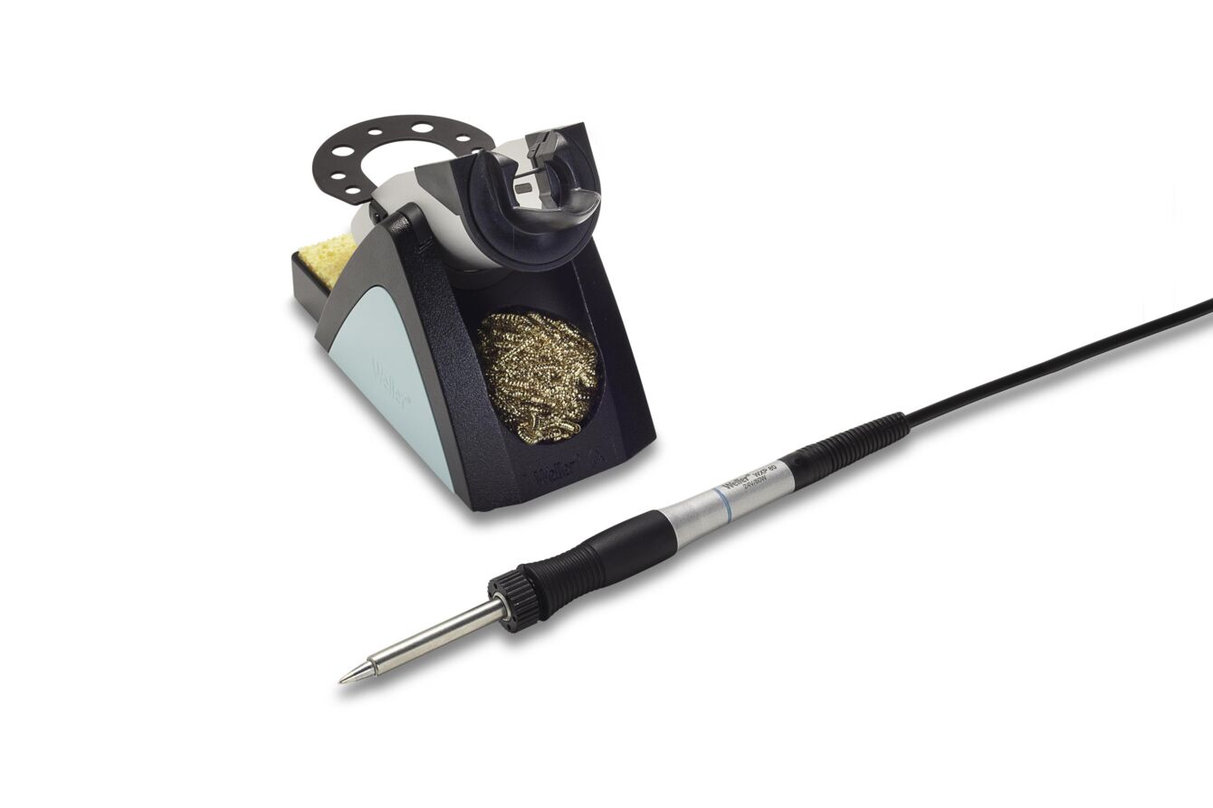 The image shows a soldering iron with a cable and a soldering iron stand. The stand is black with gray and metallic elements and includes a fine, metallic cleaning spiral.