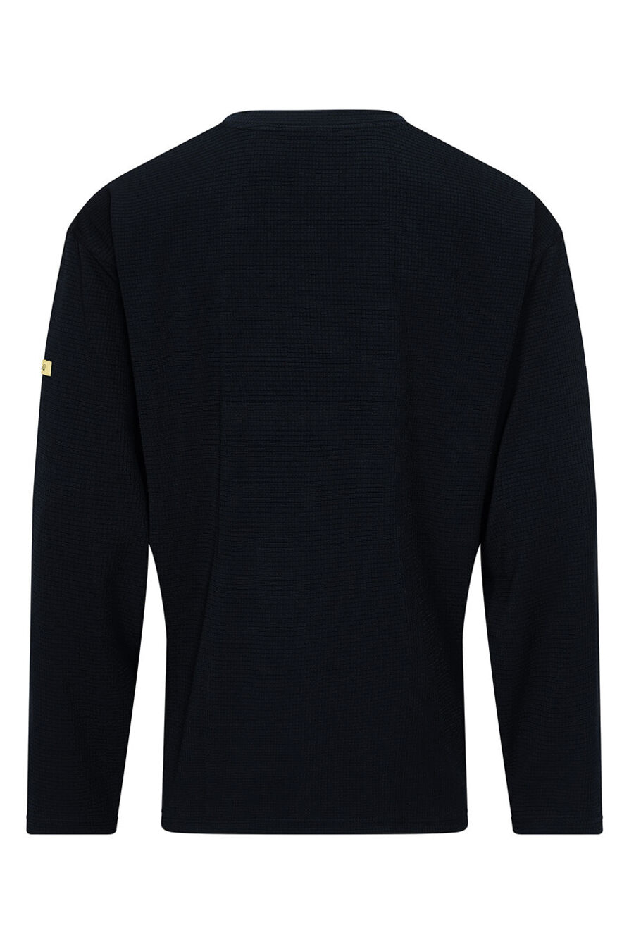 The image shows a black, long-sleeved top made of a textured fabric. It features a simple cut with a round neckline and a small, yellow detail on one sleeve.