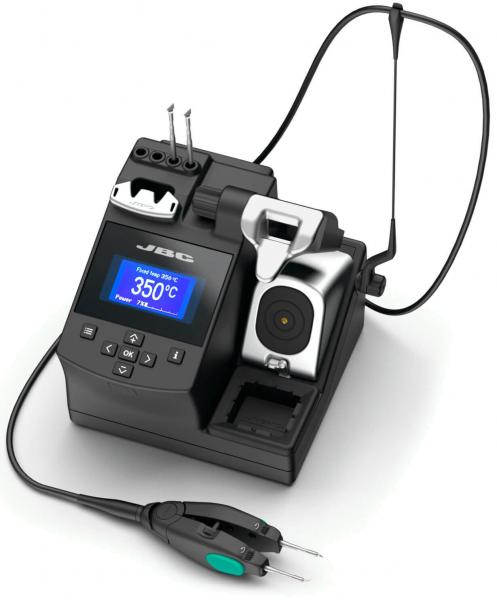 The image shows a black soldering station with a digital display in the center. It has several connections, including two soldering tips and a holder for the tool. A wired device is connected.