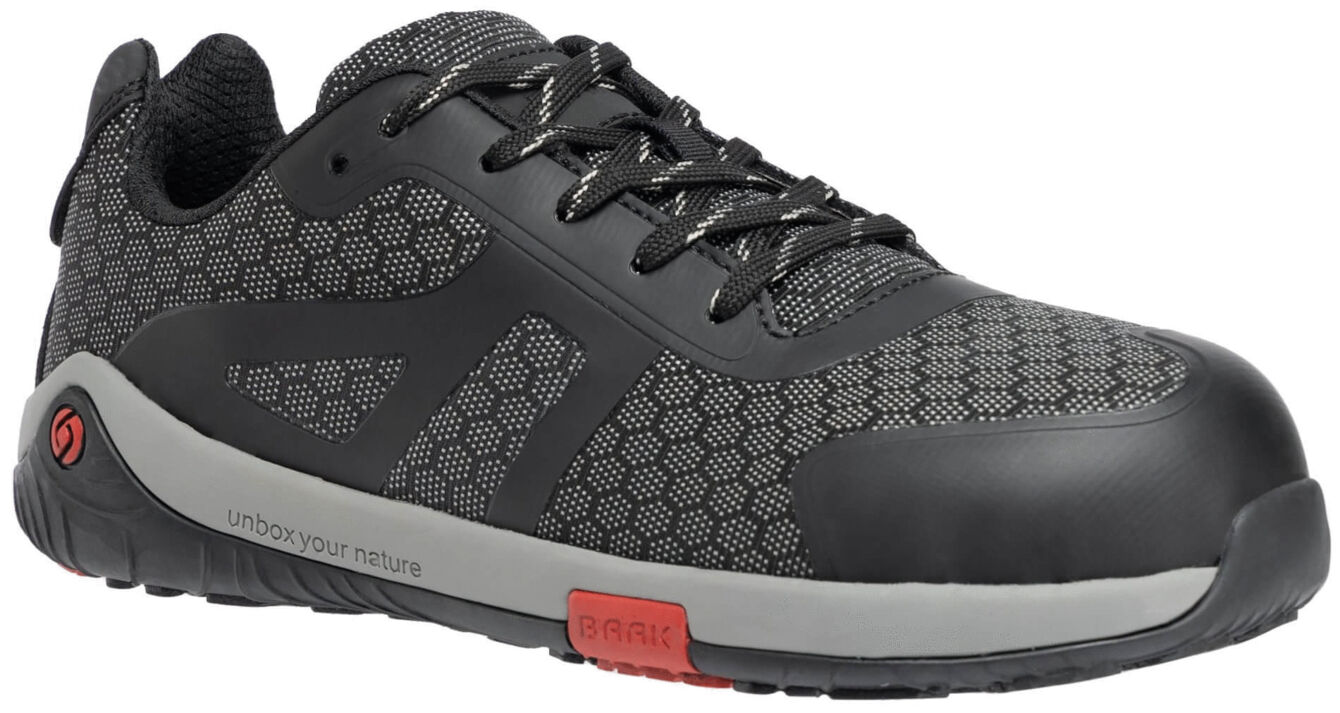 The shoe is black with gray, hexagonal patterns. It features a sturdy, round toe, a padded tongue, and laces. The sole is flat and has a red accent.