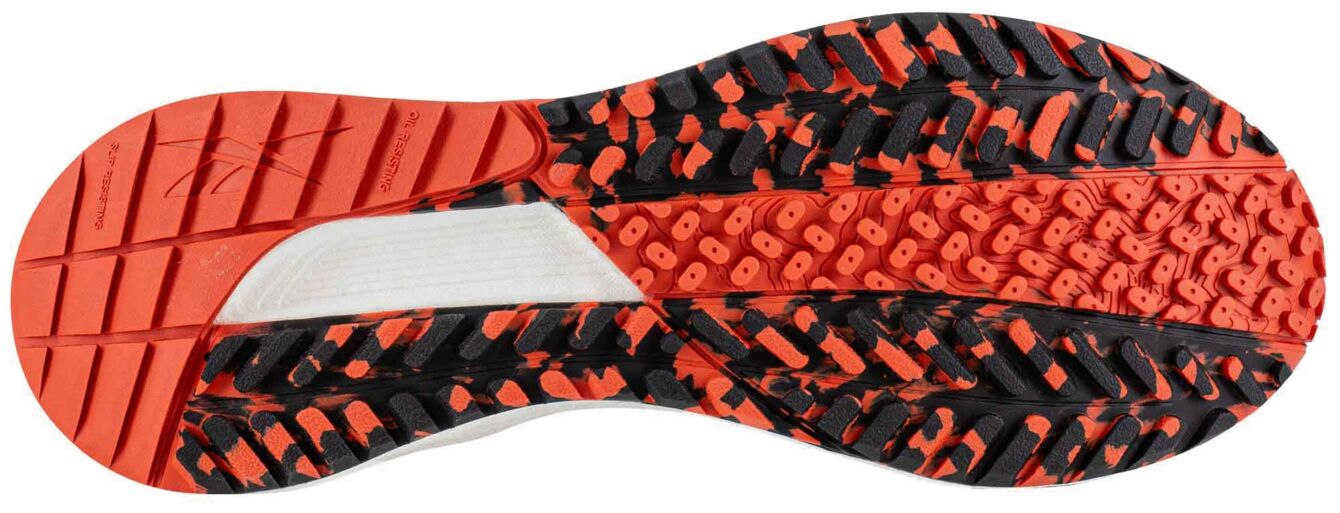 The image shows the sole of a sports shoe. The sole is designed in a pattern of red and black, with raised dots and grooves for better grip. The center is in a gray area.