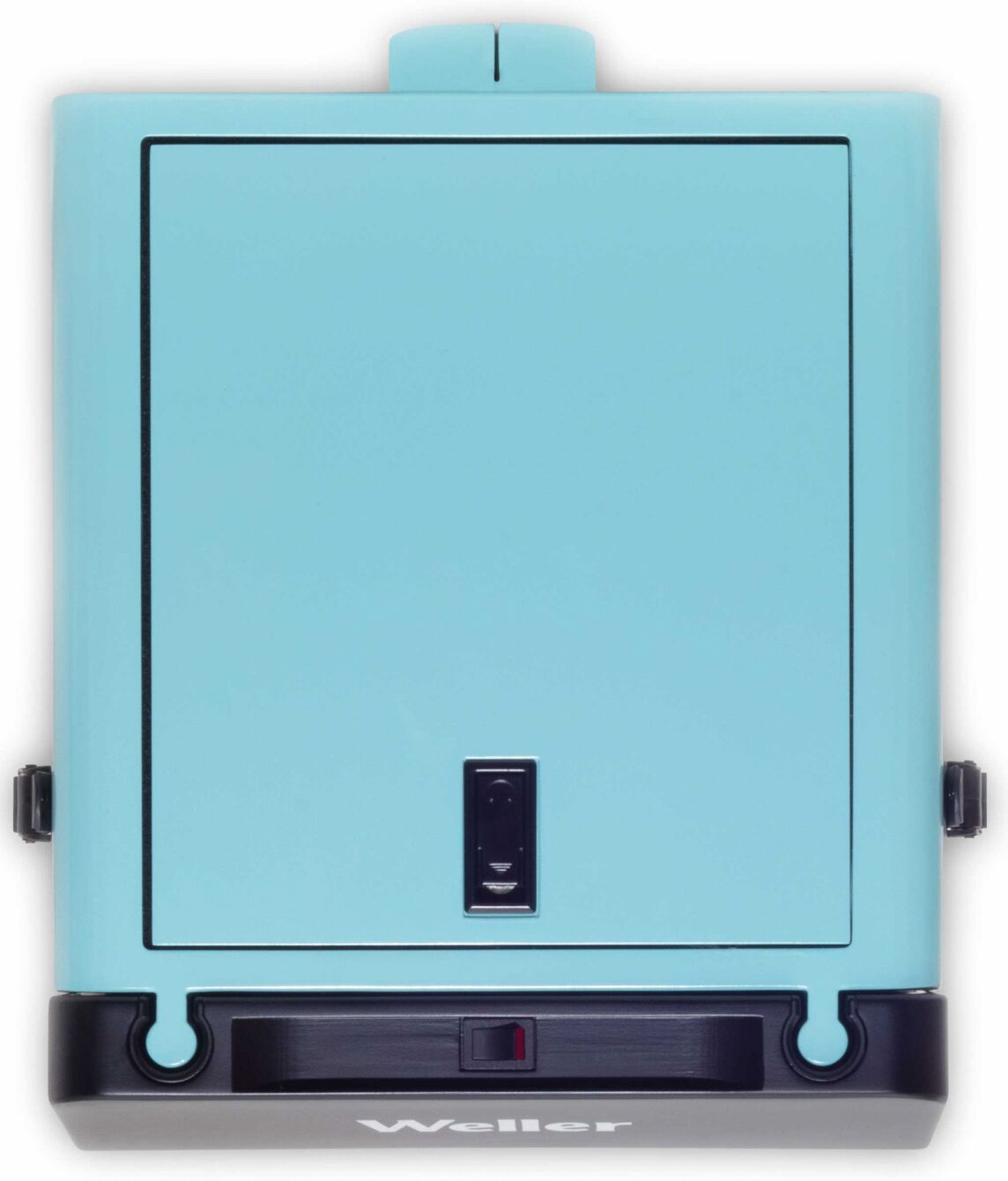 The image shows a rectangular, turquoise box with a flap on top and a black lower area. Inside, there is a small lamp switch.