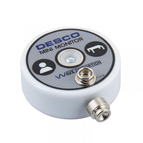 The image shows a round, white mini-monitor with a smooth top. On the top are symbols and the text "DESCO MINI MONITOR" as well as a connection on the side.