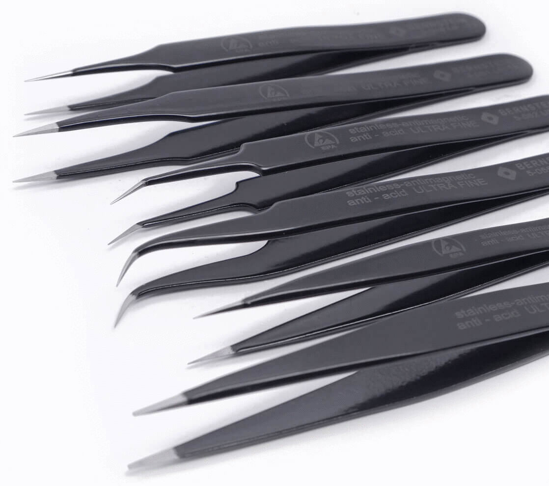 The image displays an arrangement of eight black tweezers, designed in various shapes and sizes. They are made of stainless steel and are intended for precise work.