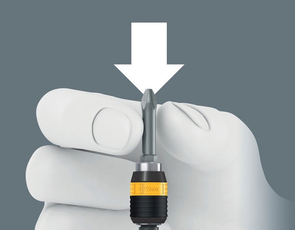 The image shows a hand in a white glove holding a screwdriver with a gray bit and a yellow handle. Above the hand is a downward-pointing arrow.