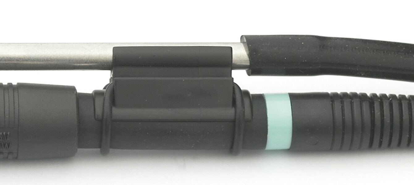 The image shows a plug and a cable. The plug is black with a blue ring. A metallic rod runs alongside it, partially covered by a black rubber protector.